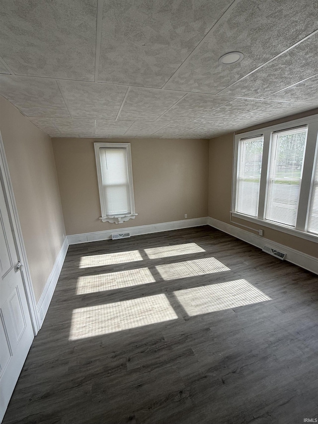 unfurnished room with baseboards, wood finished floors, and visible vents