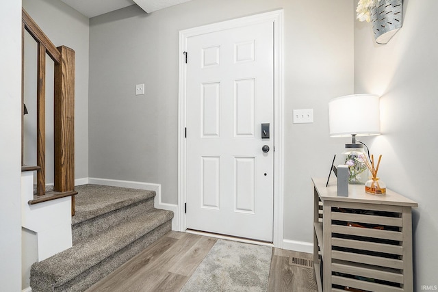 entrance foyer featuring baseboards, stairs, and wood finished floors