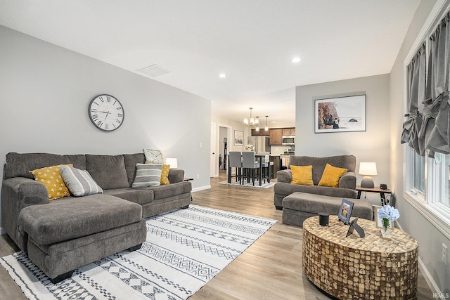 living area with baseboards, recessed lighting, light wood-style flooring, and an inviting chandelier