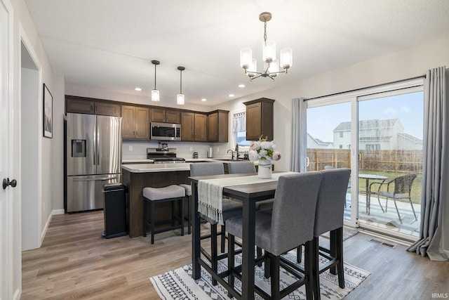 dining area featuring light wood-style floors, visible vents, baseboards, an inviting chandelier, and recessed lighting