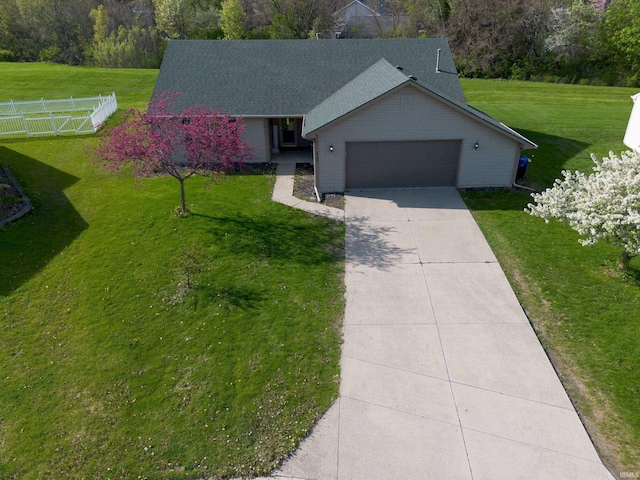 ranch-style house with fence, an attached garage, driveway, and a front lawn