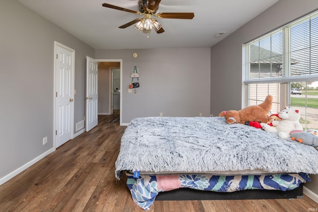bedroom with visible vents, baseboards, dark wood-type flooring, and multiple windows