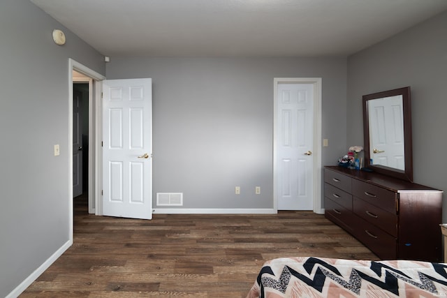 bedroom featuring baseboards, visible vents, and dark wood finished floors