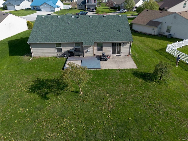 back of house with a fenced backyard, a residential view, a shingled roof, and a patio area