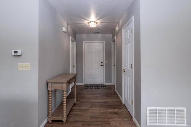 doorway with baseboards, dark wood-style floors, and visible vents