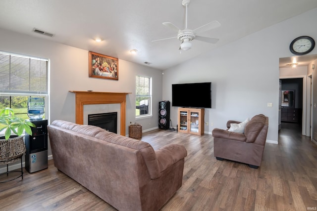 living room with visible vents, a tiled fireplace, wood finished floors, and vaulted ceiling