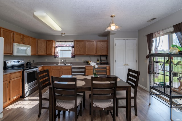 kitchen featuring visible vents, wood finished floors, stainless steel electric range, a sink, and white microwave