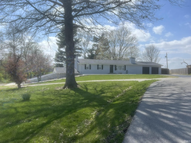 ranch-style home featuring fence, driveway, and a front yard
