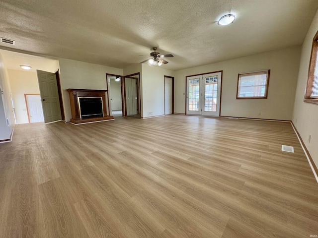 unfurnished living room with ceiling fan, visible vents, and light wood finished floors