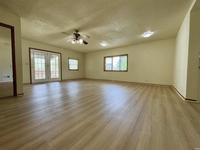 spare room featuring ceiling fan, a textured ceiling, baseboards, light wood-type flooring, and visible vents