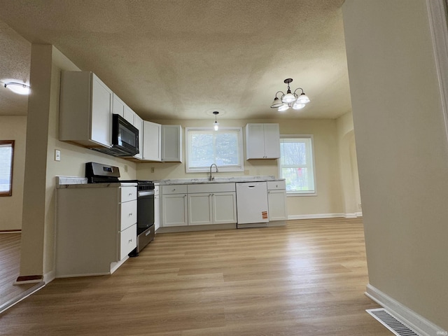 kitchen featuring a textured ceiling, white dishwasher, black microwave, light wood-type flooring, and gas stove