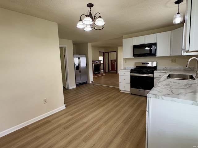 kitchen with white cabinets, a sink, light countertops, stainless steel appliances, and light wood-type flooring