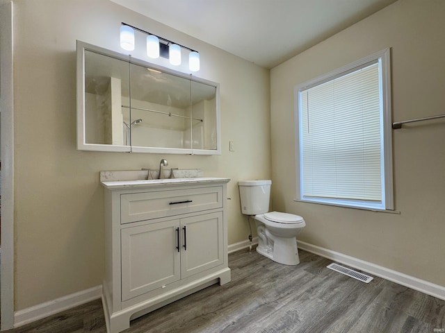 full bath featuring visible vents, vanity, wood finished floors, toilet, and baseboards