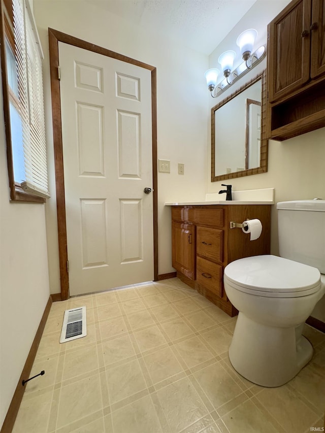 half bathroom featuring visible vents, baseboards, toilet, and vanity