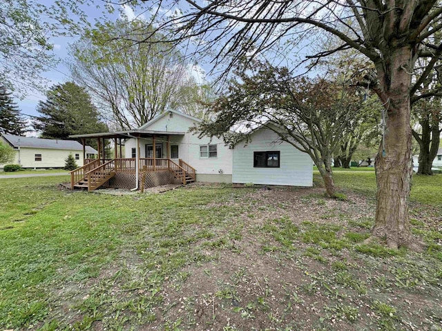 rear view of house featuring covered porch, a lawn, and stairway