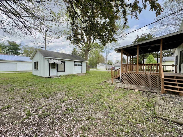 view of yard featuring a wooden deck, an outbuilding, and a detached garage