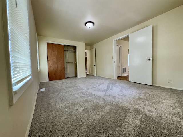 unfurnished bedroom featuring carpet floors, baseboards, a closet, and visible vents