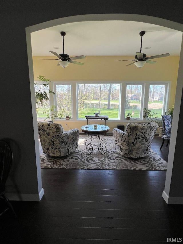 living area with baseboards, ceiling fan, and wood finished floors