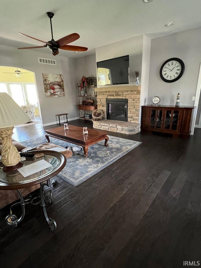 living area with ceiling fan, visible vents, a fireplace, wood finished floors, and baseboards