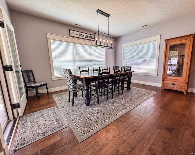 dining space with an inviting chandelier, baseboards, visible vents, and dark wood finished floors