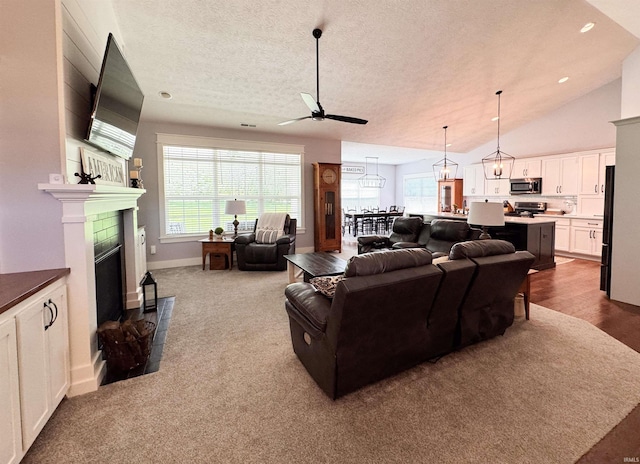 living room with a ceiling fan, a textured ceiling, visible vents, a fireplace, and lofted ceiling