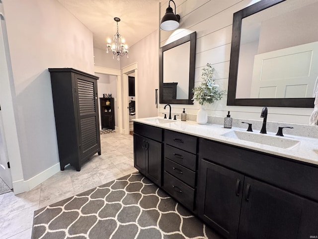 bathroom with an inviting chandelier, a sink, baseboards, and double vanity