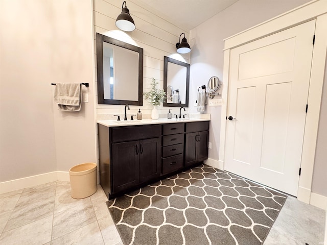 bathroom with a sink, baseboards, and double vanity