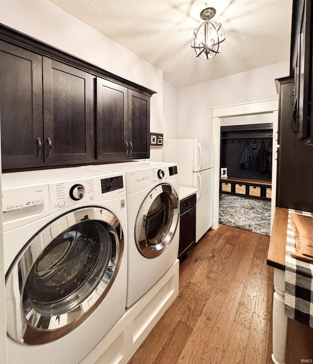 laundry area with separate washer and dryer, a textured ceiling, cabinet space, and wood-type flooring