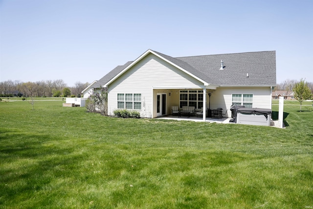 back of property with roof with shingles, a lawn, a patio area, a hot tub, and fence