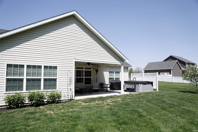 back of house with fence, a hot tub, a patio area, a ceiling fan, and a yard