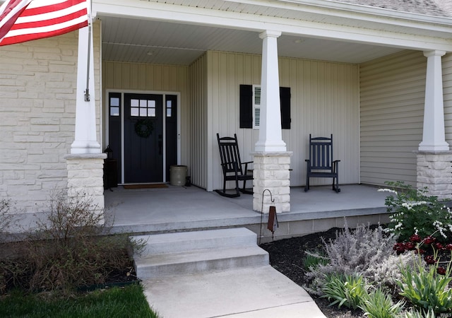 view of exterior entry featuring covered porch and stone siding
