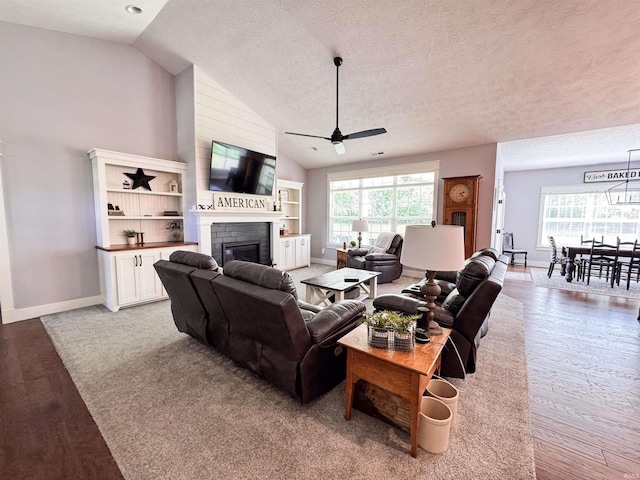 living area featuring wood finished floors, a ceiling fan, a healthy amount of sunlight, and a fireplace