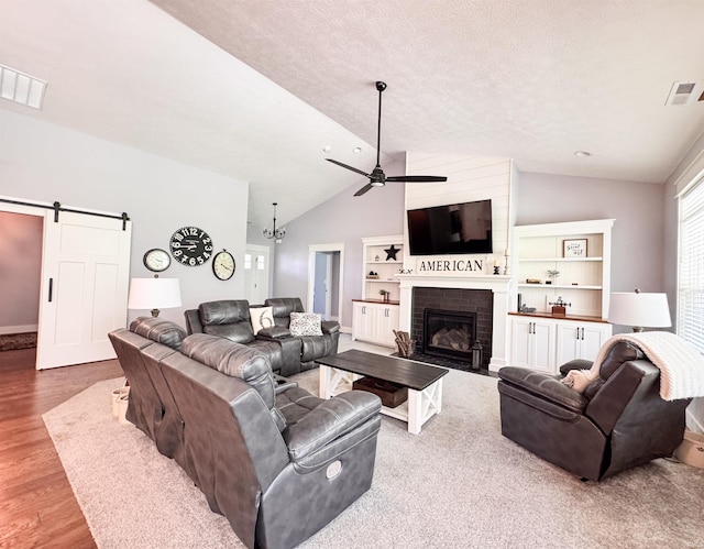 living room featuring visible vents, a barn door, ceiling fan, and lofted ceiling