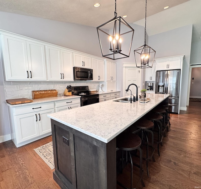 kitchen with appliances with stainless steel finishes, a sink, high vaulted ceiling, white cabinets, and an inviting chandelier