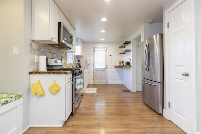 kitchen featuring open shelves, light wood finished floors, stainless steel appliances, recessed lighting, and white cabinetry