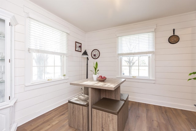 dining room with crown molding, wood walls, and dark wood-type flooring
