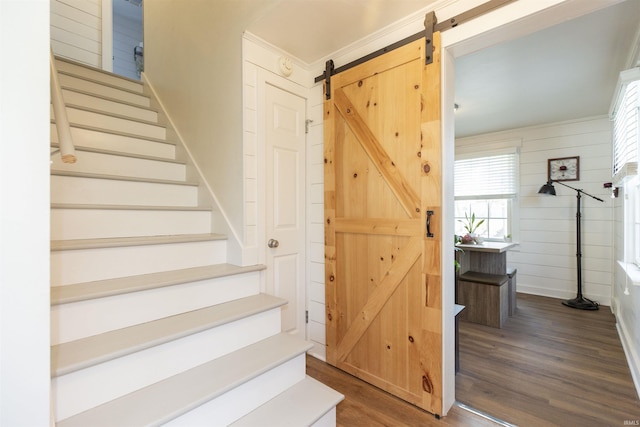 staircase with baseboards, a barn door, and wood finished floors