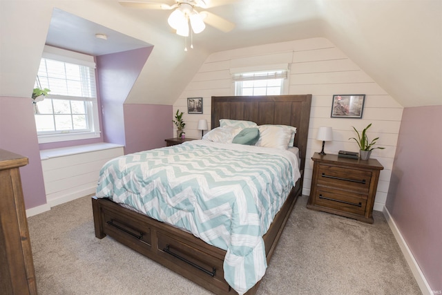 bedroom with wood walls, multiple windows, vaulted ceiling, and light carpet