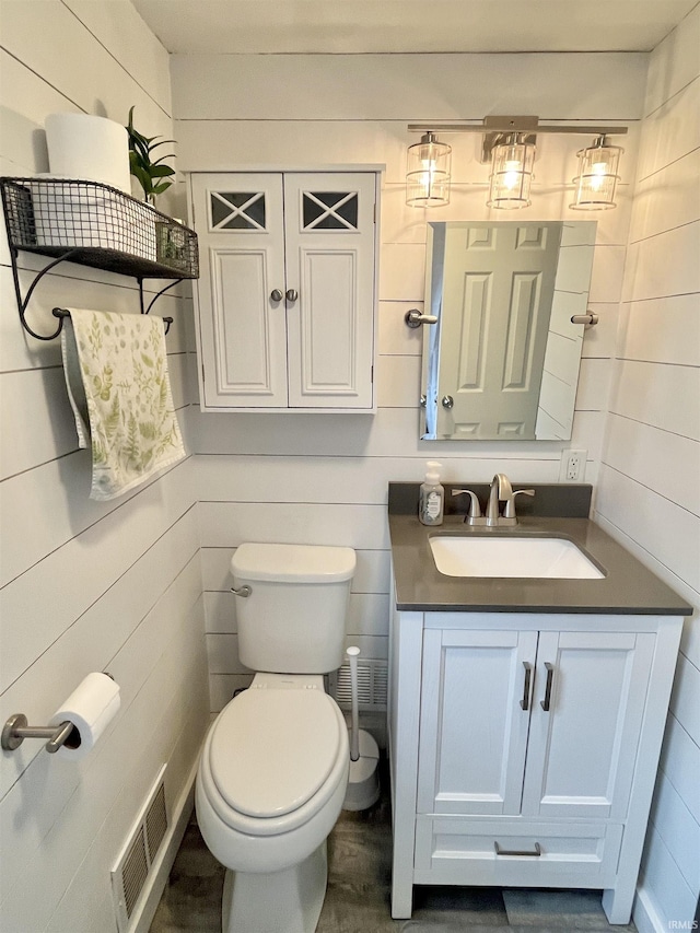 half bath with toilet, visible vents, and vanity