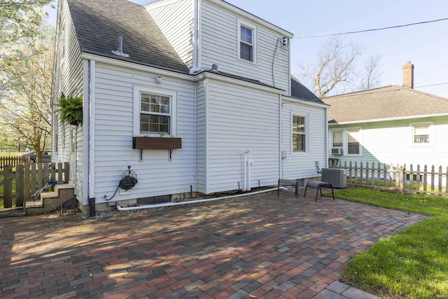 back of property featuring a shingled roof, a patio area, fence, and cooling unit