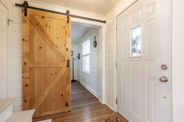foyer entrance featuring crown molding, a barn door, and wood finished floors