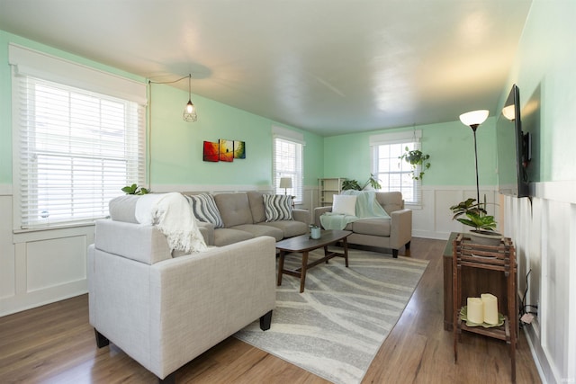 living area with wainscoting, a decorative wall, and wood finished floors