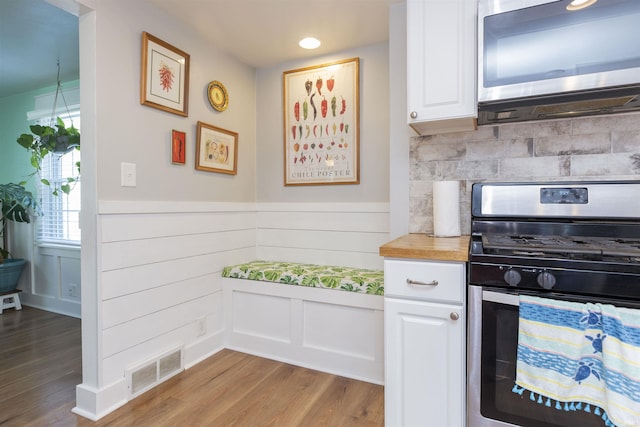 kitchen with visible vents, white cabinetry, wood finished floors, and stainless steel appliances