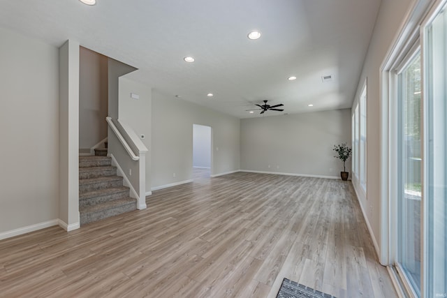 unfurnished living room featuring ceiling fan, light wood-type flooring, stairway, baseboards, and recessed lighting