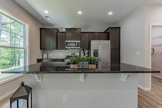 kitchen featuring dark brown cabinetry, stainless steel appliances, a spacious island, and visible vents