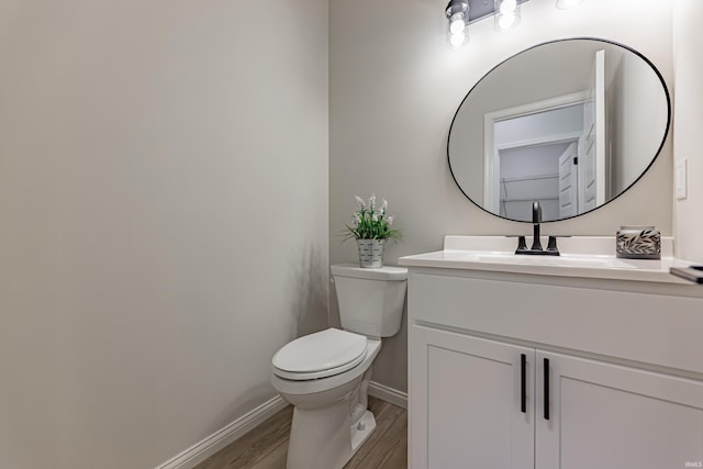 bathroom with toilet, baseboards, wood finished floors, and vanity