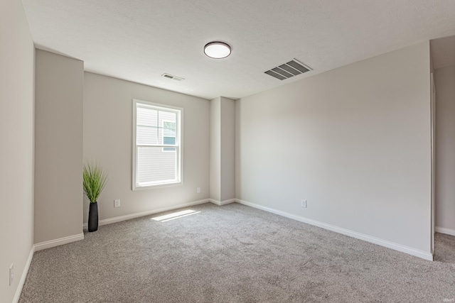 carpeted spare room featuring baseboards and visible vents