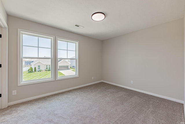 carpeted spare room featuring baseboards and visible vents