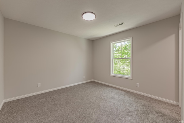 carpeted spare room featuring baseboards and visible vents