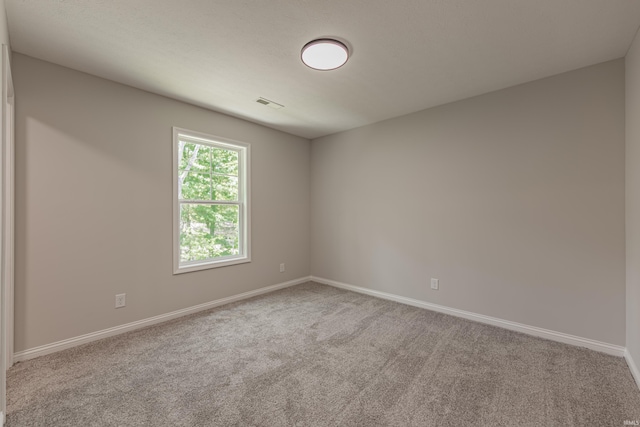 empty room with baseboards, carpet flooring, and visible vents